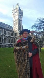 Dr James Robinson in front of the Otago University clock tower. James is wearing a korowai provided by the Heritage New Zealand staff as a mark of respect and appreciation for James’ academic achievement. Ngatiwai Kaumatua gave special consent for James to wear a korowai off-stage as part of graduation day, even though James does not claim an iwi connection to Ngatiwai or any other iwi. (Image sourced HNZ Media Release)